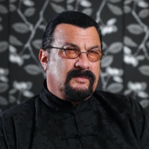 Photo of Steven Seagal wearing a eye wear and a black dress.